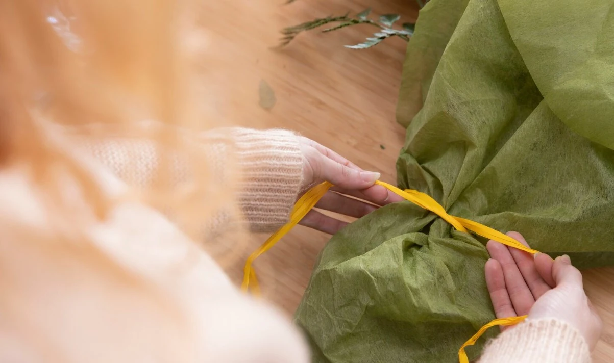 Producción de prendas de vestir de tejido natural con textil verde y cinta métrica.